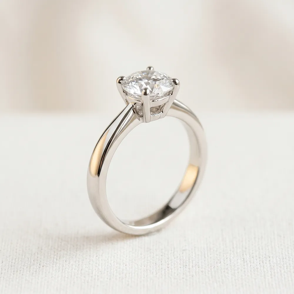 Close-up of a 1-carat round solitaire engagement ring in a white gold setting on a neutral background